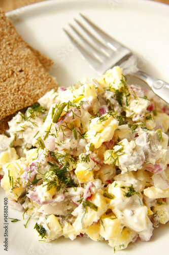 Herring and potato salad with capers on white dish