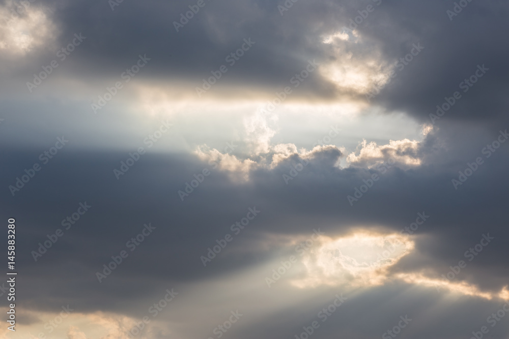 A close up of some dark clouds with powerful sunrays cutting through some holes A close up of some dark clouds with powerful sunrays cutting through some holes