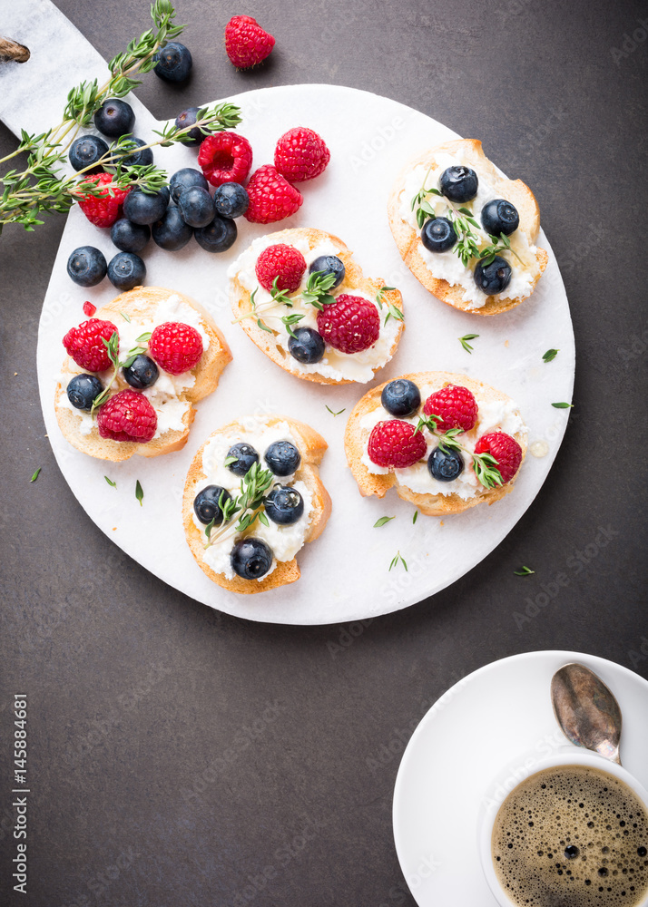 Cup of coffee with berry and goat cheese sandwiches on marble cutting board, top view, copy space. Cup of coffee with berry and goat cheese sandwiches on marble cutting board, top view, copy space.