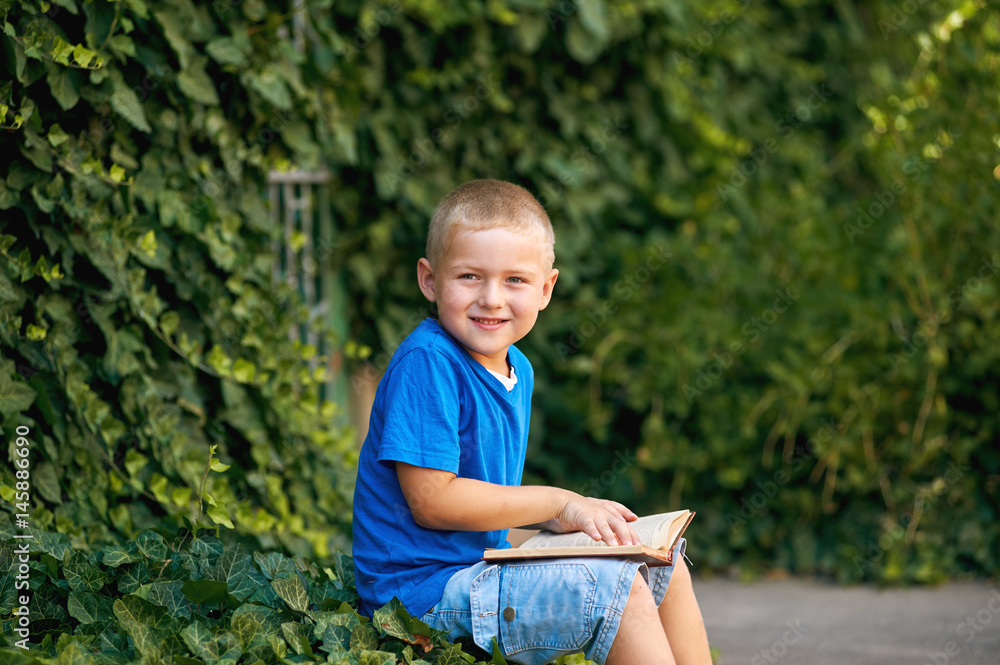 boy reading a book outdoors . The concept of preschool education boy reading a book outdoors . The concept of preschool education