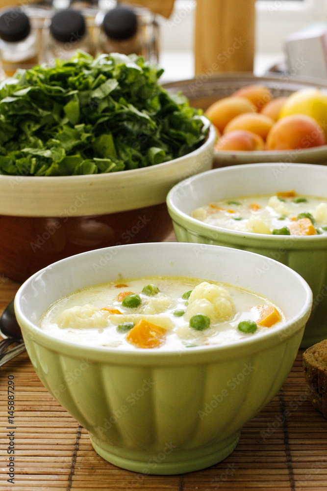 Seasonal vegetable soup with cheese spread on bowl