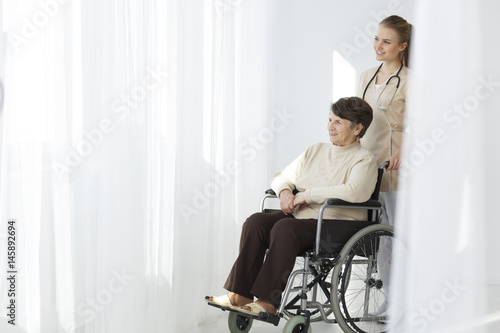 Senior woman on wheelchair and caregiver