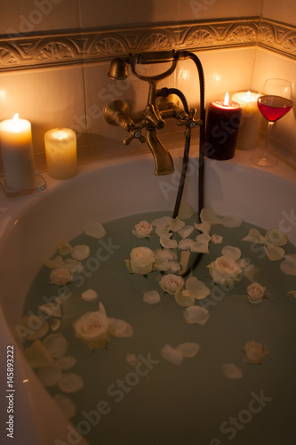 Obraz na płótnie Take a bath with rose petals and candles. Romantic evening in the bathroom with wine and candles w salonie