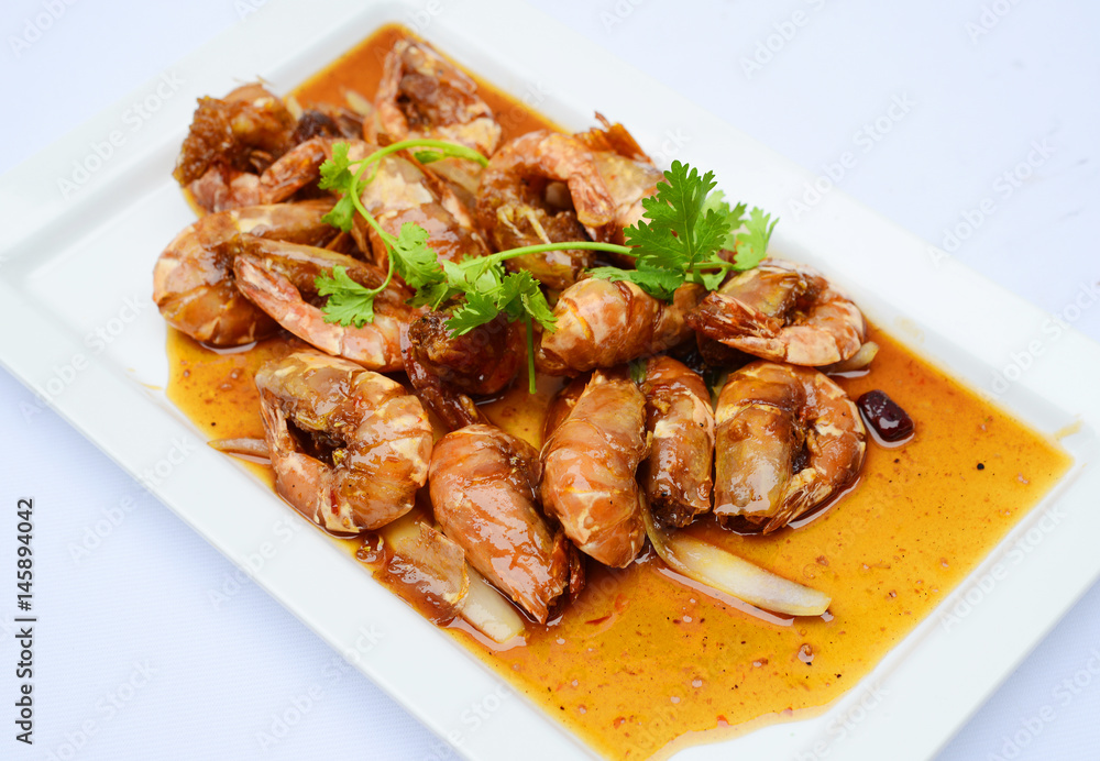 Sauteed shrimp with sauce and herbs on white platter Sauteed shrimp with sauce and herbs on white platter