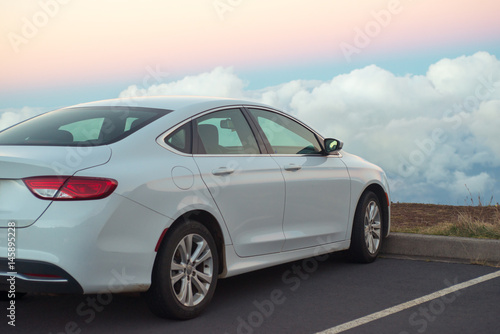 White car in mountains above the clouds at sunset or sunrise © Nuli_k
