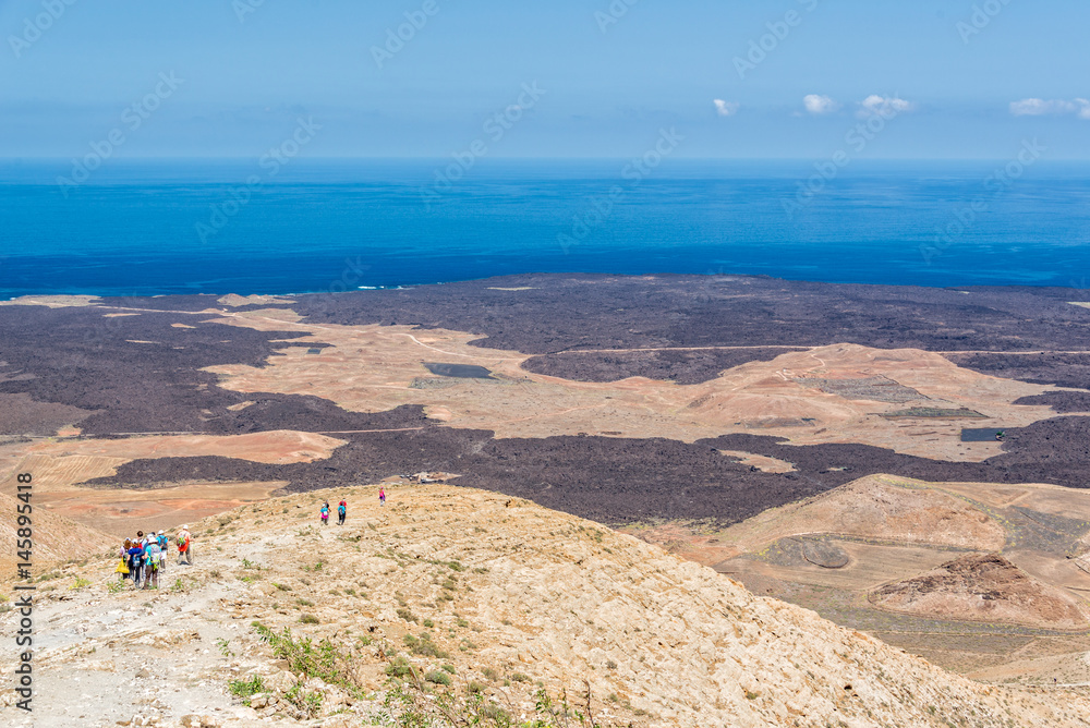 Group of hikers on Caldera Blanca, old volcano in Lanzarote, Canary islands, Spain