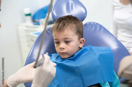 Young boy is looking cautious at the dentist. Concept photo of pediatric dentistry  introduction to dentistry  prevention dentistry. Ongoing relationship is important in child dentistry.