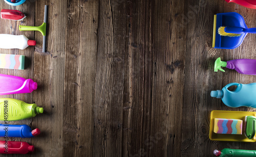 Variety of colorful house cleaning products, rustic wooden table, top view shot. Spring cleanup concept. 