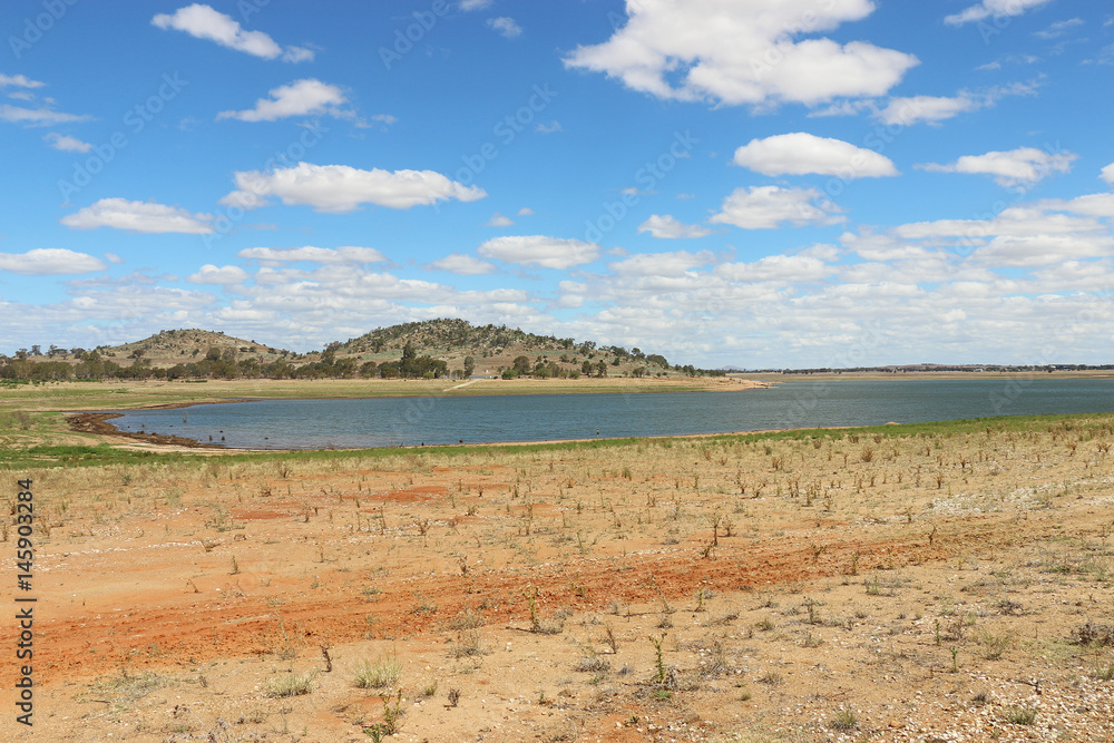 Reservoir with receding water levels and bright blue sky