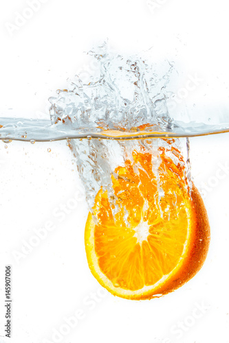 Fototapeta Naklejka Na Ścianę i Meble -  orange halves falling into water on white background.
