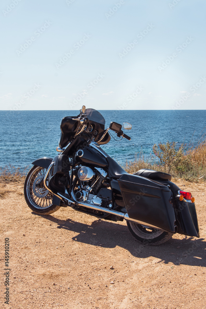 Obraz premium Black motorcycle on beautiful seacoast and blue sky. Prairie, steppe, summer.