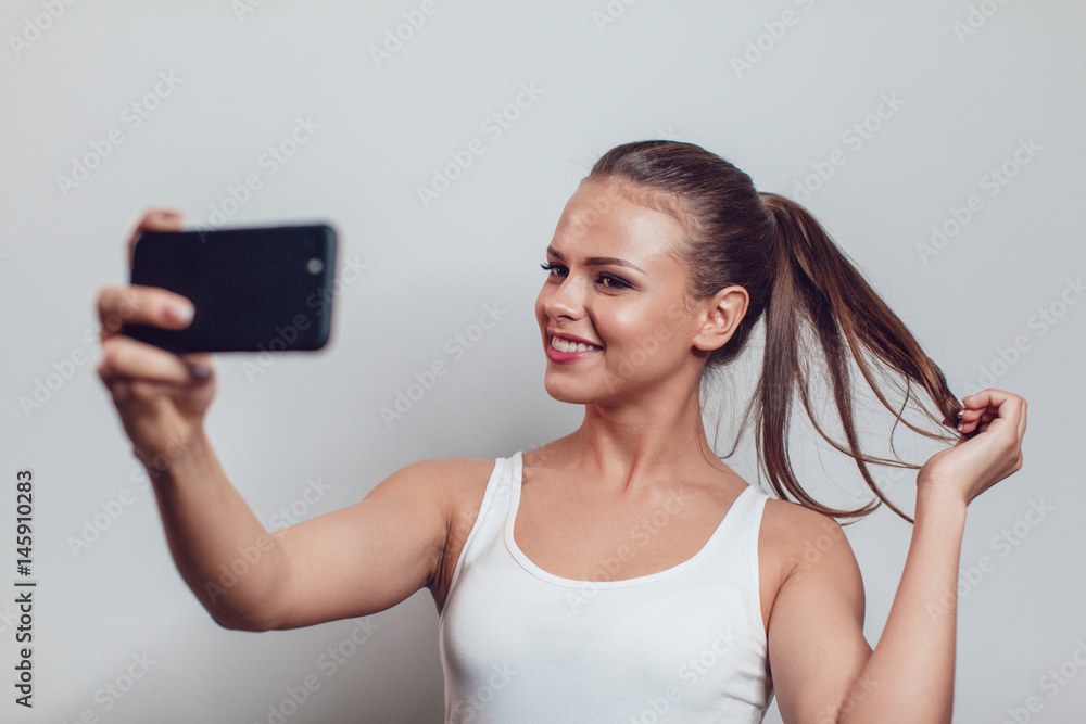 Young smiling woman having fun and make selfie on white background.