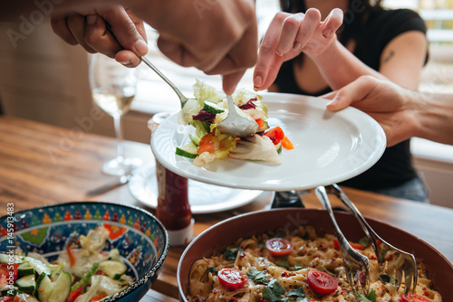 People putting food on the plate and having dinner together photo