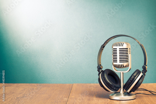 Microphone and headphones on table in front aquamarine wall background
