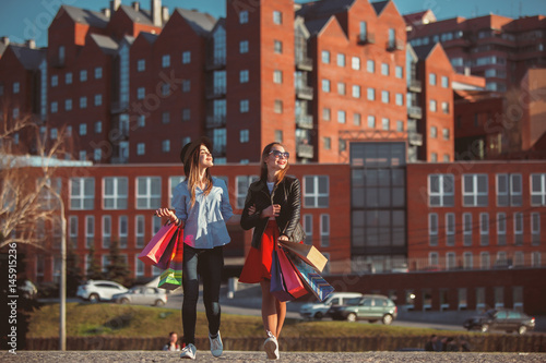 Two girls walking with shopping on city streets