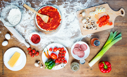 top view of pizza ingredients, tomatoes, salami and mushrooms on wooden tabletop