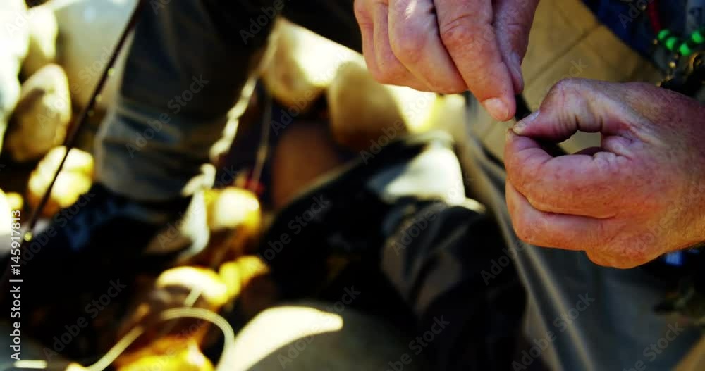 Fly fisherman preparing string to tie on hook Fly fisherman preparing string to tie on hook
