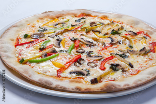 Fresh pizza with pepper, cheese and mushrooms on white plate photo