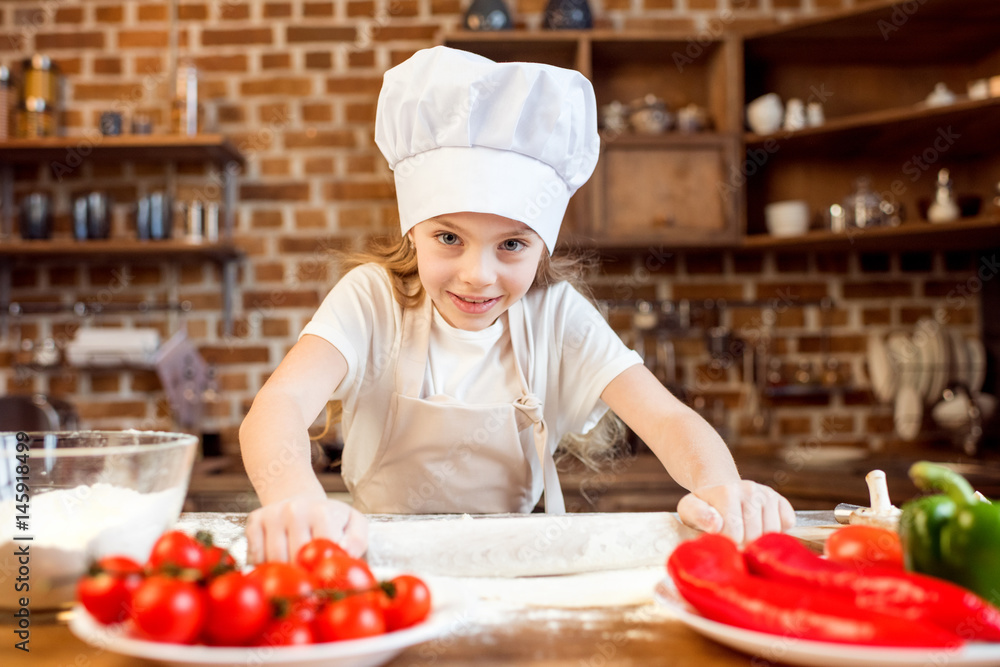 little girl making pizza dough with pizza ingredients on foreground little girl making pizza dough with pizza ingredients on foreground
