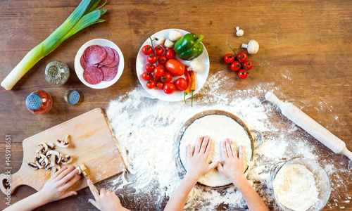 Foto top view of children making pizza dough and preparing pizza ingredients in kitch