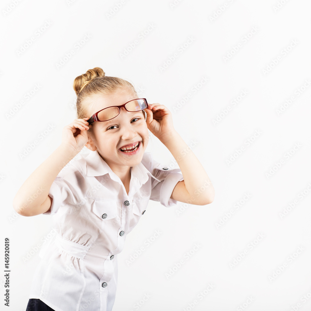Funny little girl wearing eyeglasses imitates a strict teacher against white background