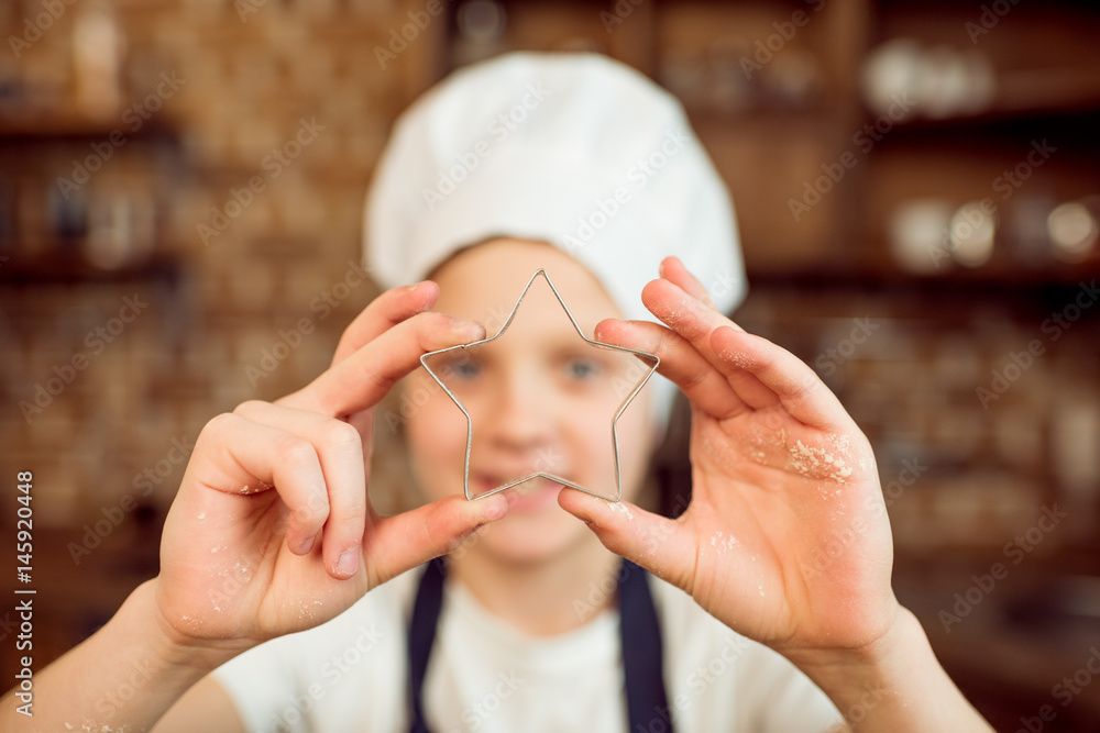Fototapeta premium boy in chef hat holding star shaped cookie cutter