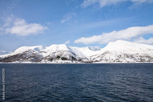 scenic view from boat trip on beautiful snowy fjords in norwegian sea in blue sky and clouds, norway