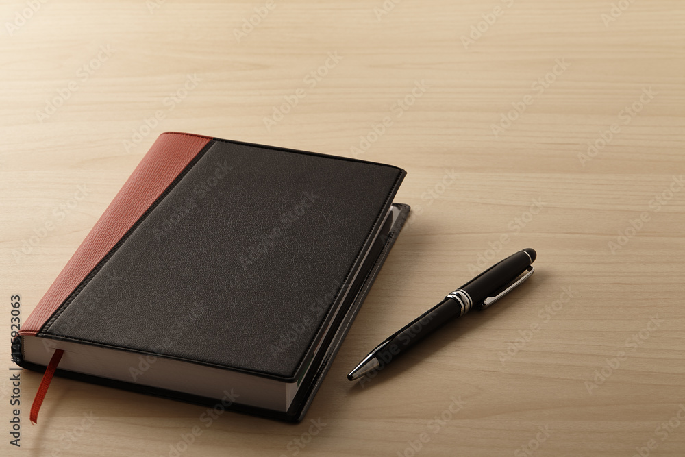 Note book and pen on the wooden table Note book and pen on the wooden table