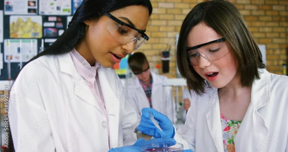 School girls experimenting with chemical in laboratory at school School girls experimenting with chemical in laboratory at school