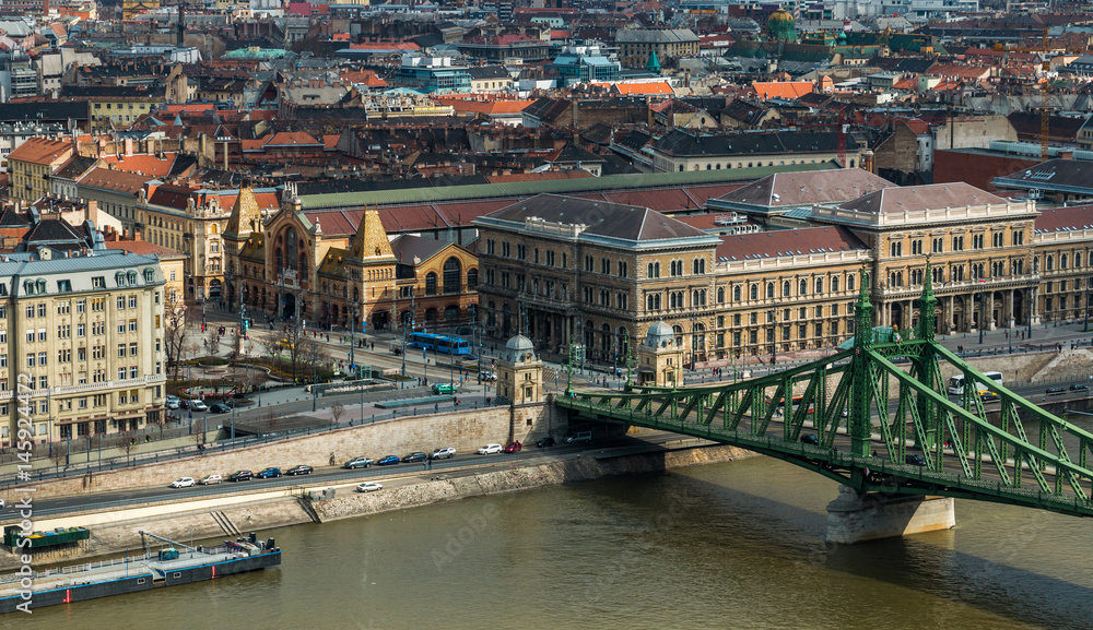 Square near Great Market Hall and Liberty Bridge over Danube river by day in Budapest, Hungary. Cityscape of Pest side view from Gellert Hill