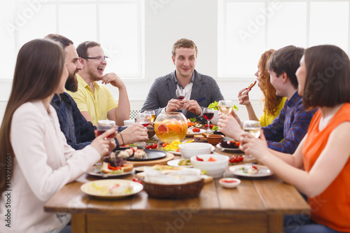 Group of happy people at festive table dinner party