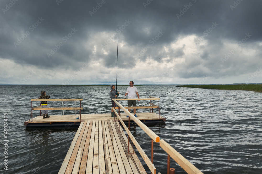 Dramatic landscape with wooden pier and fishermen