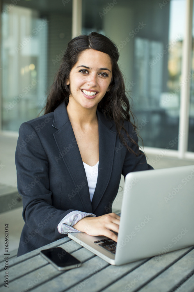 Portrait of a bussines woman working with laptop. She is wearing a black suit. Portrait of a bussines woman working with laptop. She is wearing a black suit.