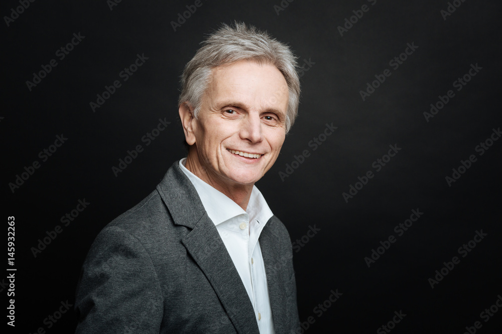 Joyful old man smiling in the black colored studio Joyful old man smiling in the black colored studio