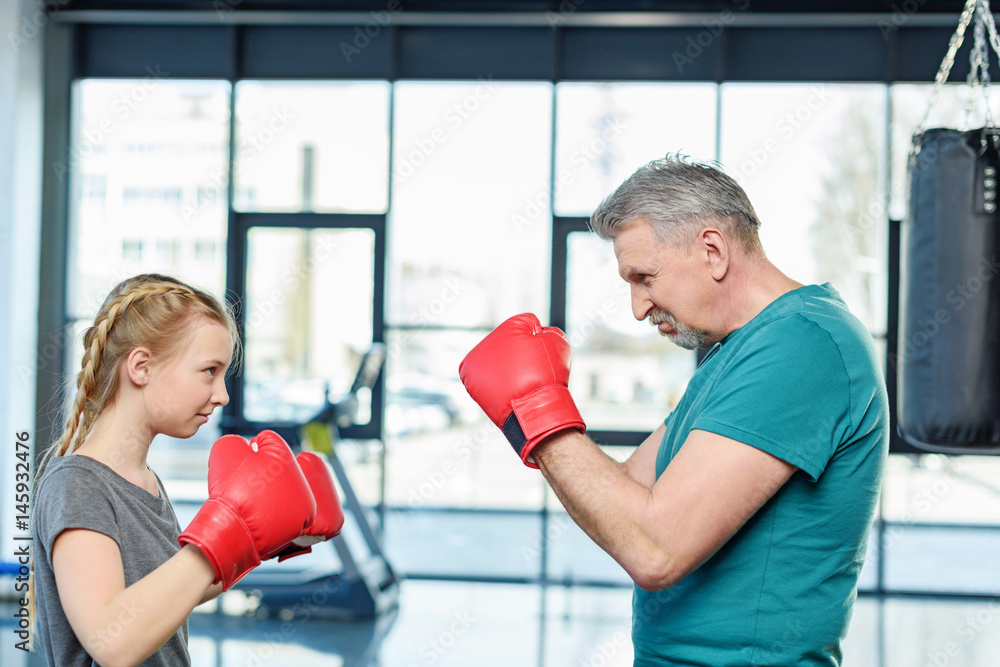 preteen girl boxing with senior trainer. Fitness manager, gym class kids concept