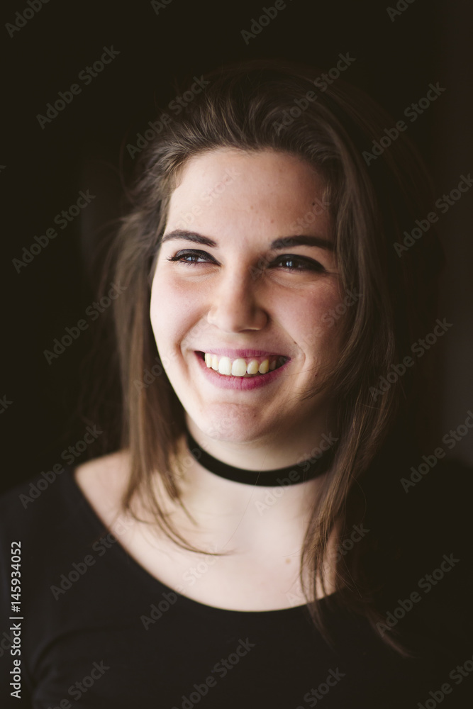 Portrait of a woman smiling. Black background. She wears a black T-shirt. Portrait of a woman smiling. Black background. She wears a black T-shirt.