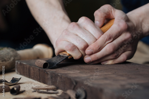 Wood carving, the master's hands work with a wooden surface, a professional does wood crafts