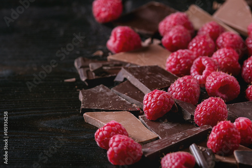 Wallpaper Mural Dark and milk chopping chocolate and chips shavings chopping chocolate with fresh raspberries heap over black burnt wooden background. Close up with space. Chocolate dessert concept Torontodigital.ca