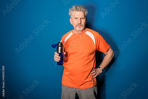 Confident mature sportsman holding bottle of water and looking at camera © LIGHTFIELD STUDIOS