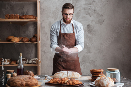 Foto Young concentrated bearded man wearing glasses baker