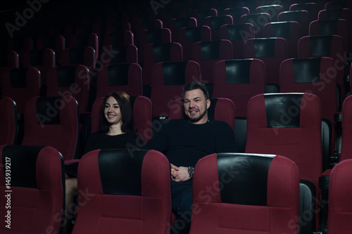 Happy romantic couple watching movie in theater