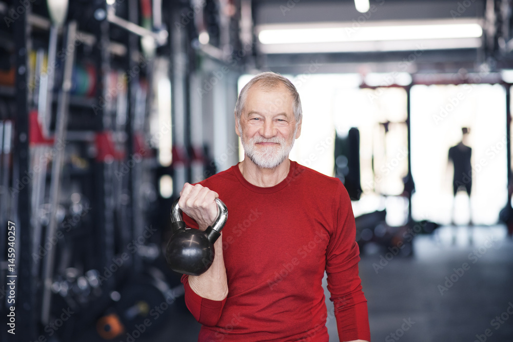 Senior man exercising with kettlebell in gym Senior man exercising with kettlebell in gym