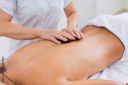 Beautician make stone massage spa for woman at wellness center