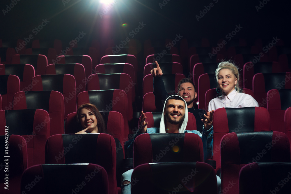 Happy smiling friends watching film in theater