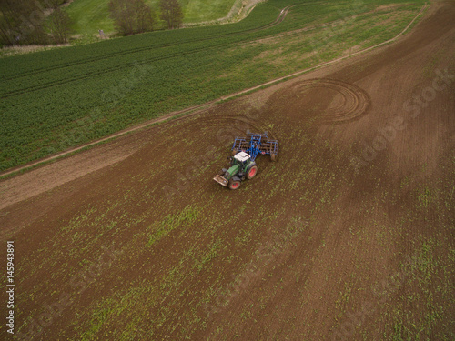 aerial view of a tractor at work - tractor plough cultivating beautiful fields - agricultural machinery
