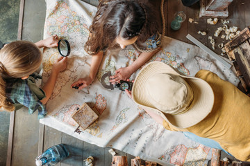 Overhead view of little kids travelers sitting together on porch with map