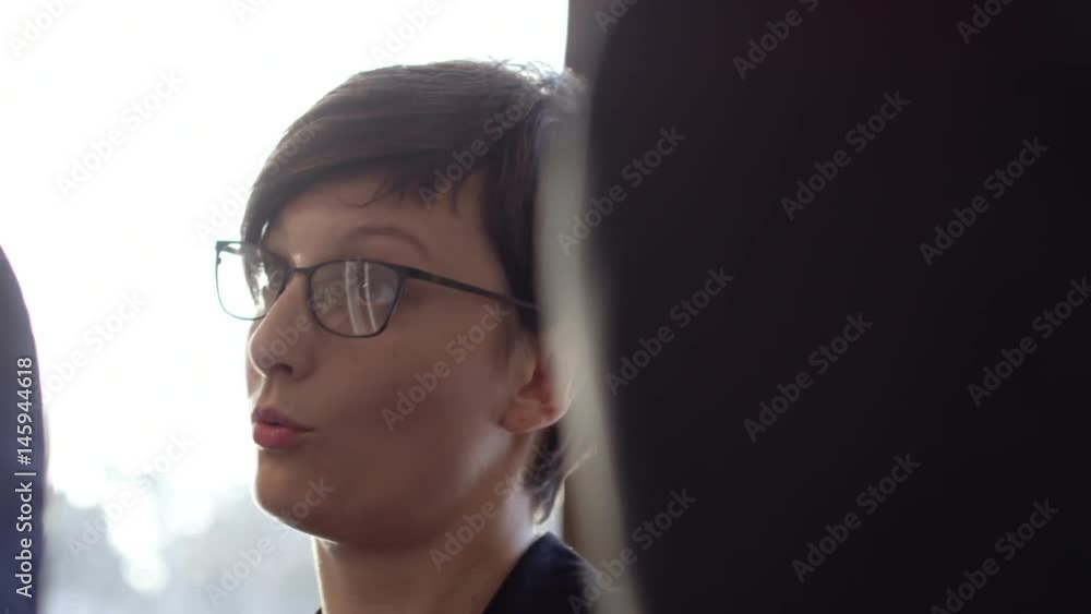 Closeup tracking shot in slow motion of brunette short-haired businesswoman in eyeglasses listening to colleagues, nodding her head and talking Closeup tracking shot in slow motion of brunette short-haired businesswoman in eyeglasses listening to colleagues, nodding her head and talking