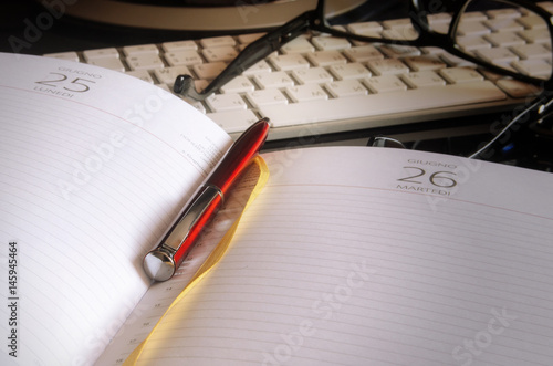 Open pages of a notepad and ball-point pen in the foreground.