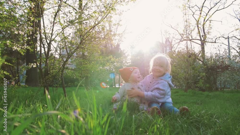 Two cute little sisters having fun together on the grass on a sunny spring day Two cute little sisters having fun together on the grass on a sunny spring day