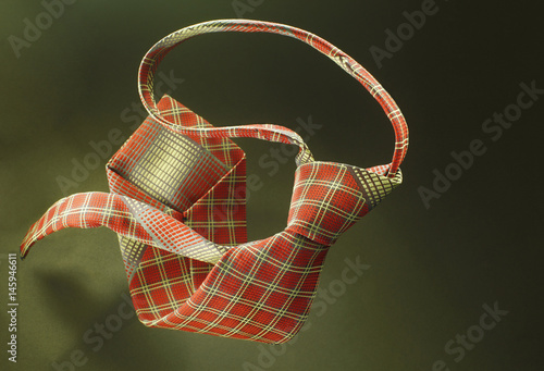 Red with yellow checkered necktie on green fabric background, fashion accessory close up